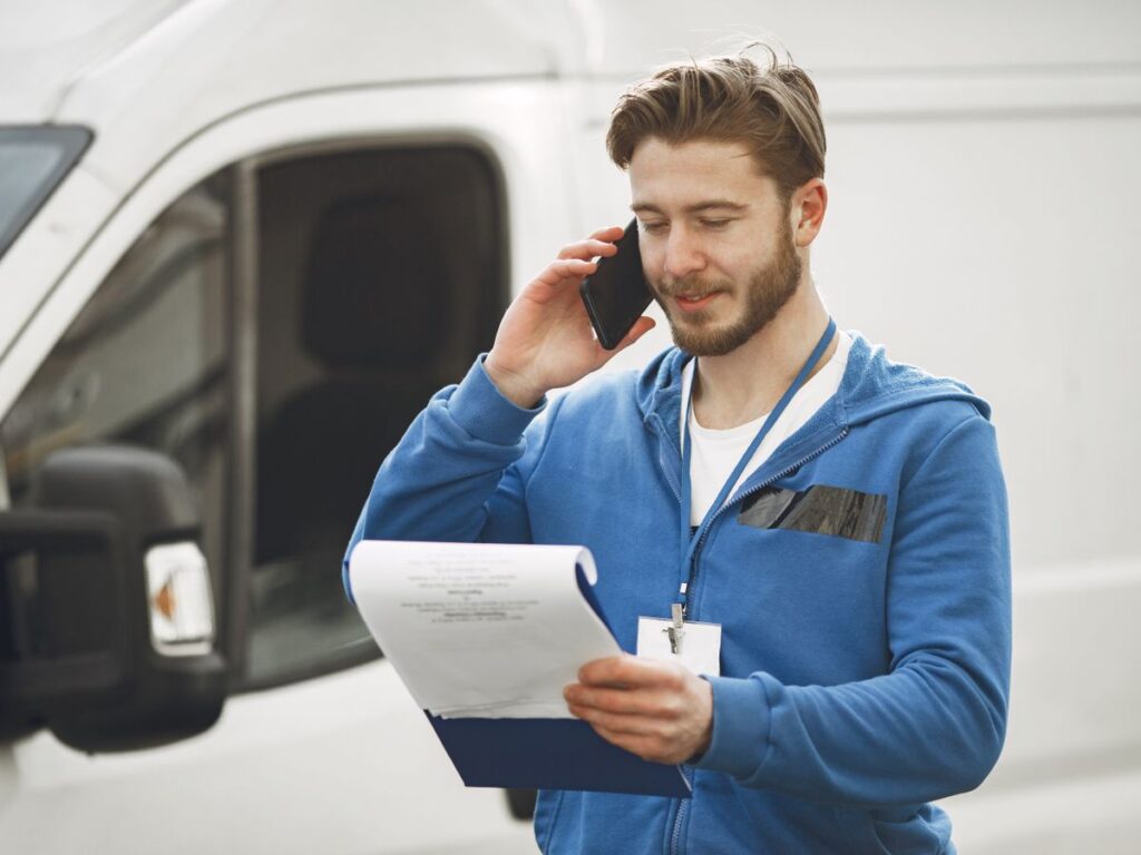 Tradesman taking a customer call beside his van while out on a job